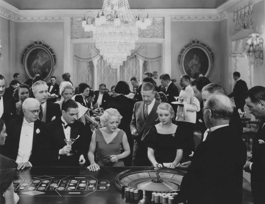 Black and white casino scene with people gathered around roulette wheel