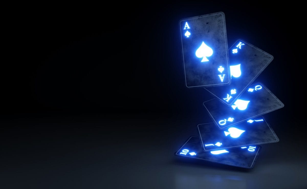 Light up blue playing cards mid air with a black background.