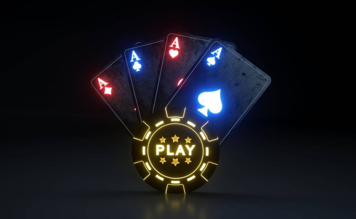 Lit up ace cards behind a lit up poker chip with a black background.