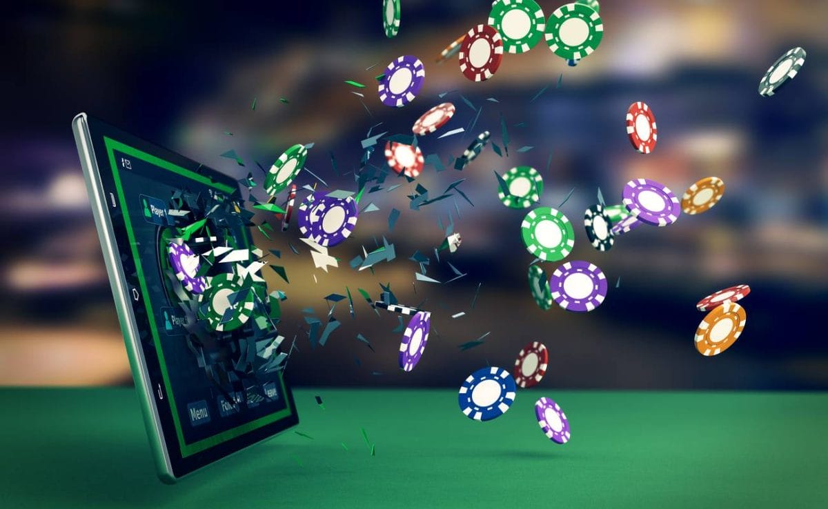 Various colored poker chips fly out of tablet screen on a green casino table.