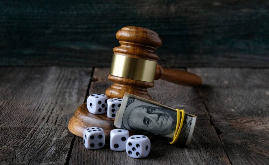 Brown gavel on multiple white dice with a roll of US dollars by its side