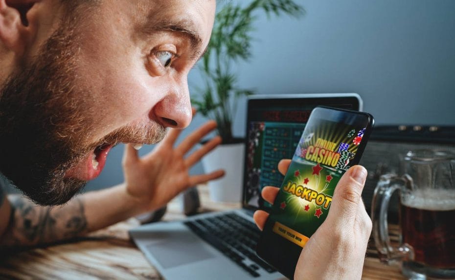Man screaming at his phone which is displaying online casino jackpot 