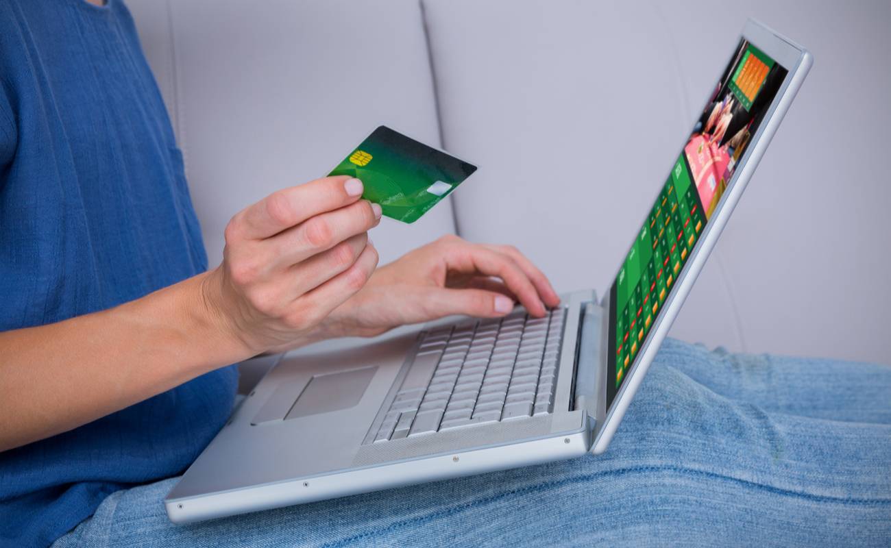 Woman using her credit/debit card to play online poker on her laptop.