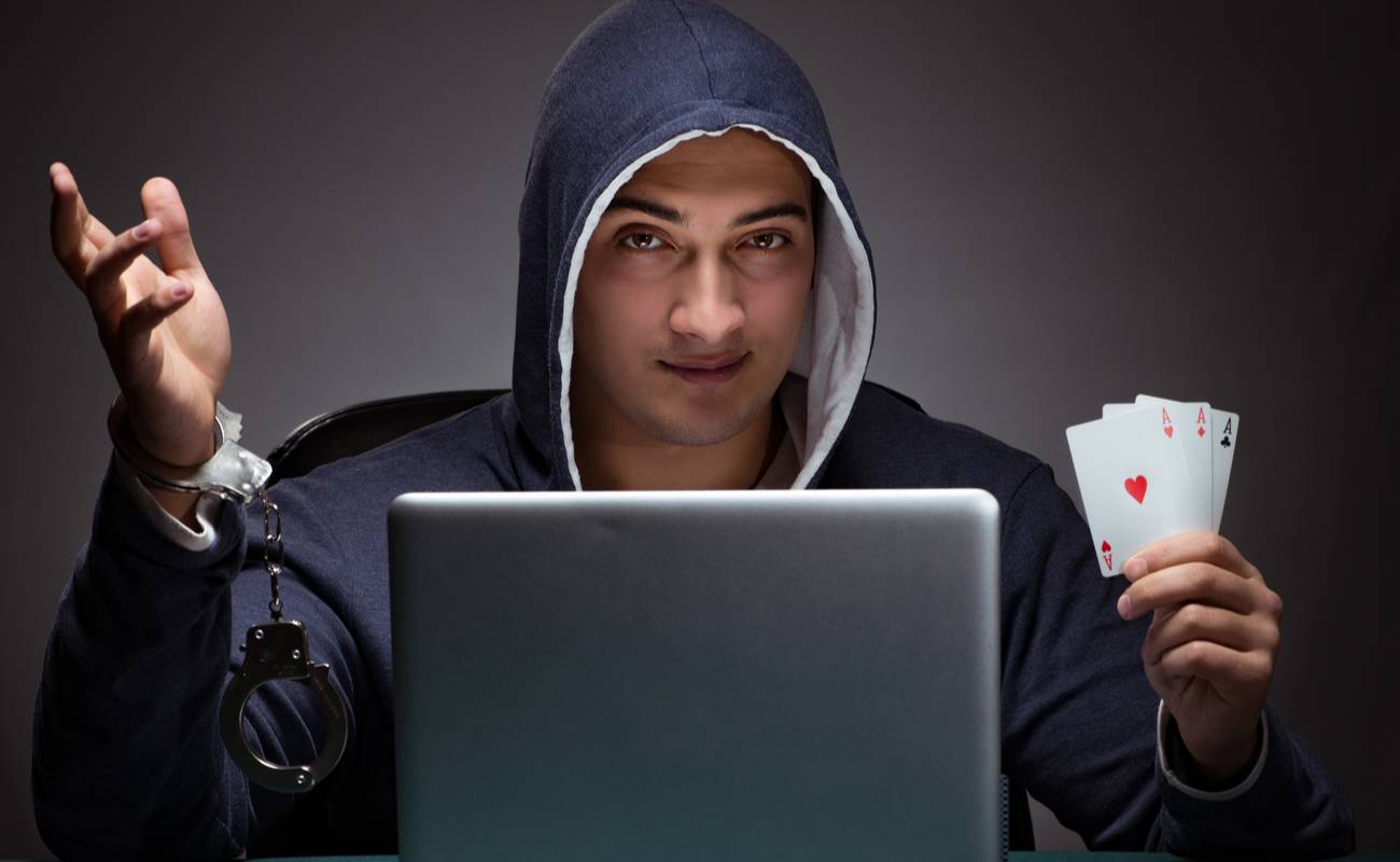 Man in hooded jumper holding cards in one hand and handcuffs in the other