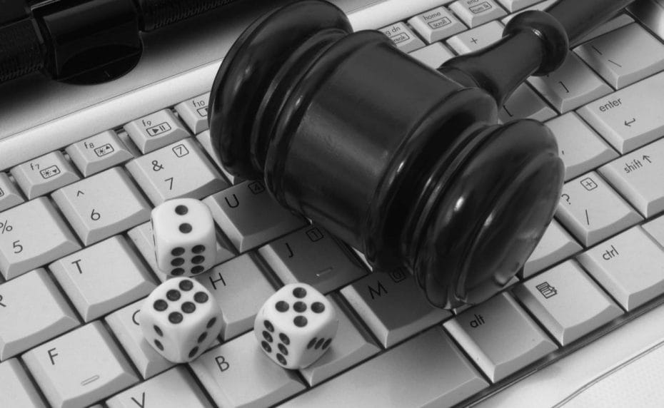 Black gavel rests on a computer keyboard with 3 dice by its side.