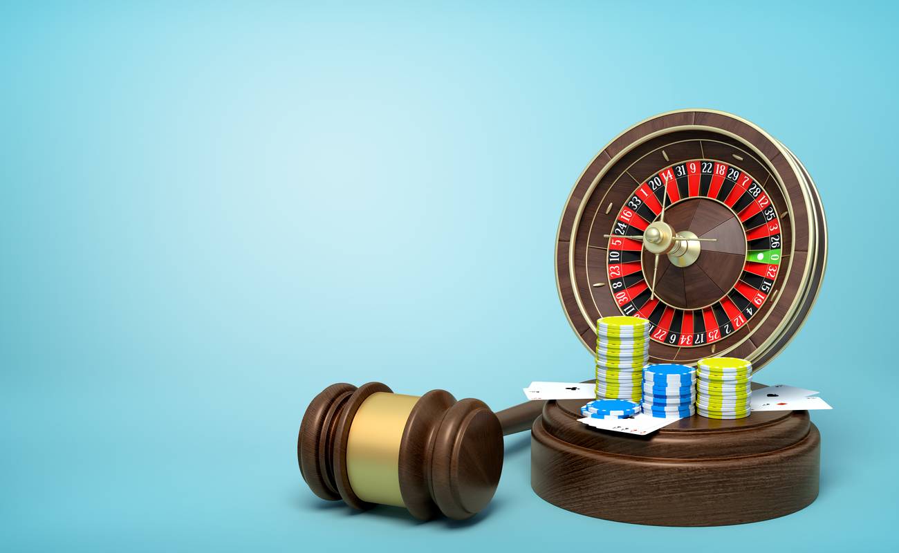 Gavel rests by a roulette table with poker chips and cards laying on it.