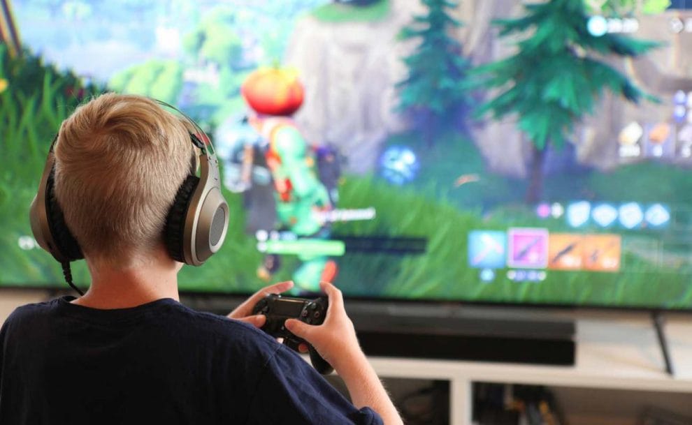 Young boy playing Fortnite on a Playstation with a headset on.