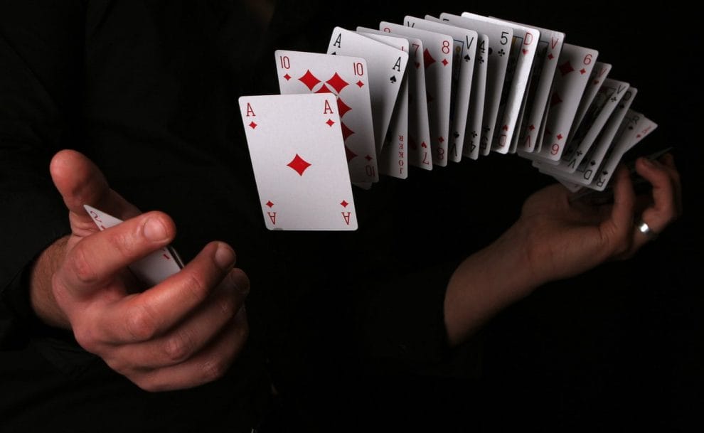 A pair of hands with cards spread across and floating in between them