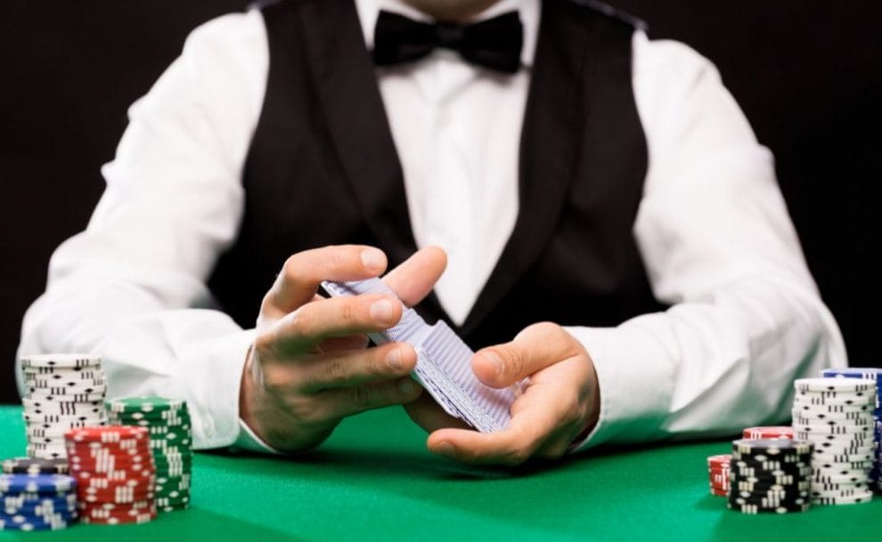 Man in smart clothes shuffling cards on a table with poker chips