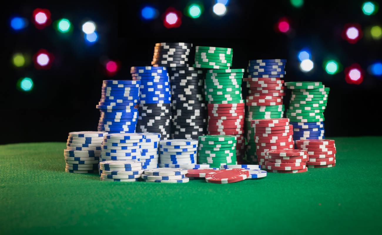 Stacks of poker chips in multiple colours on a green surface