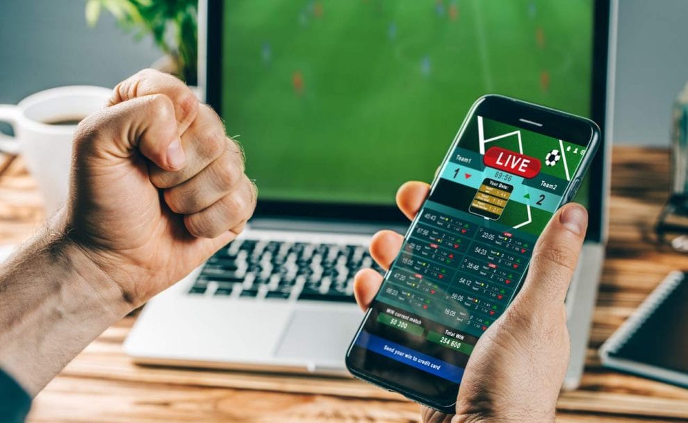 Man celebrating his win on a sports betting app with his phone in one hand