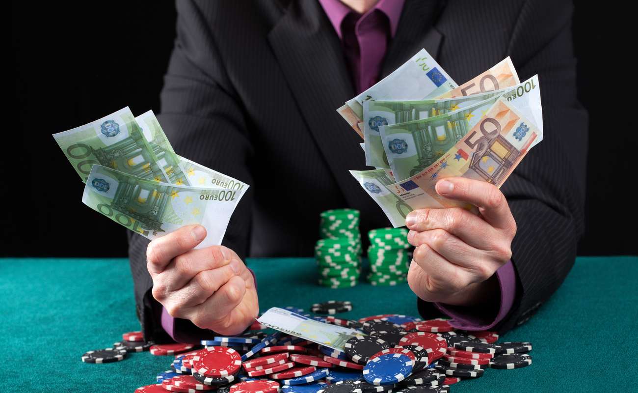 Man holding many euro notes in his hands with poker chips stacked up