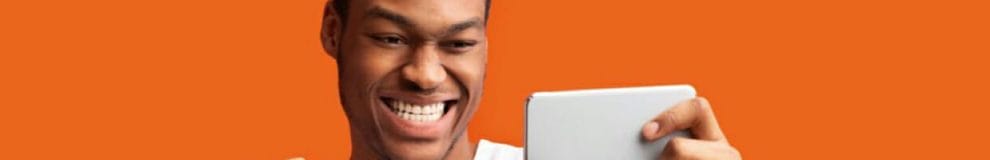 Man staring and smiling at mobile phone in front of orange background