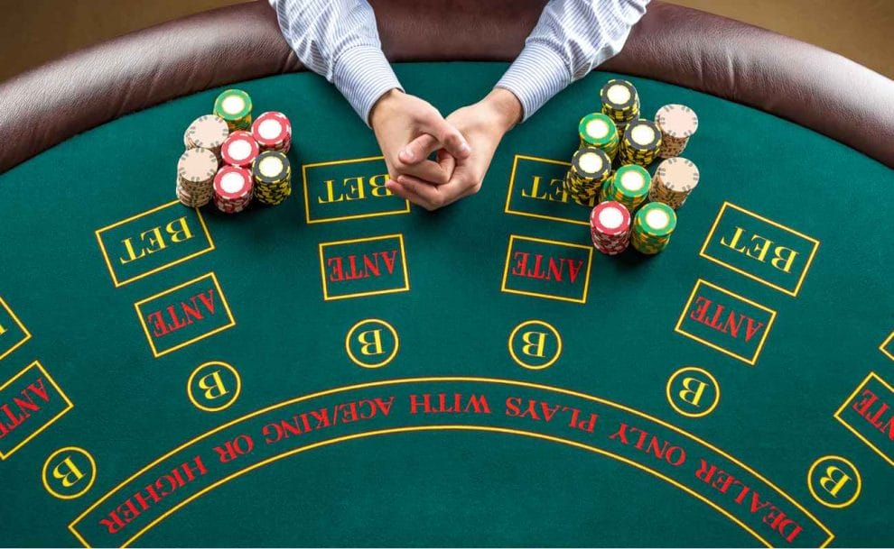 Green poker table with hands folded in between piles of poker chips