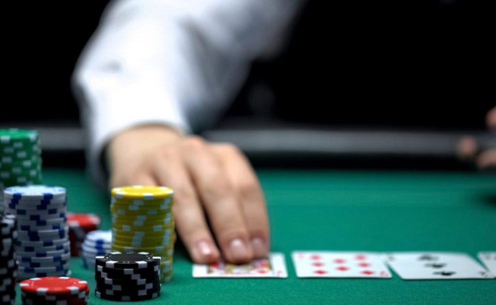 Close up of hands in between piles of poker chips on casino games table