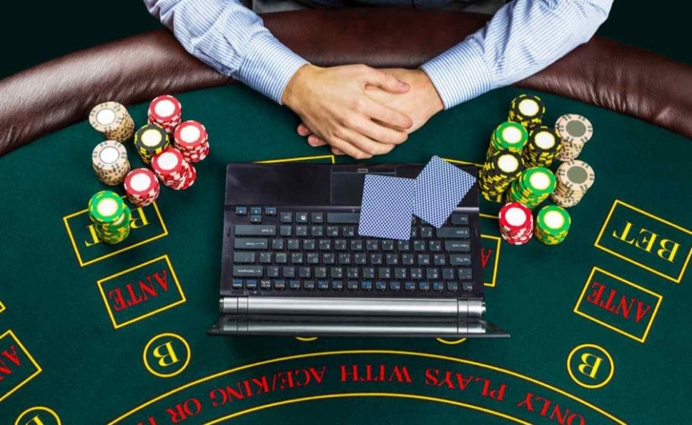 Closeup of poker player with playing cards, laptop, and chips