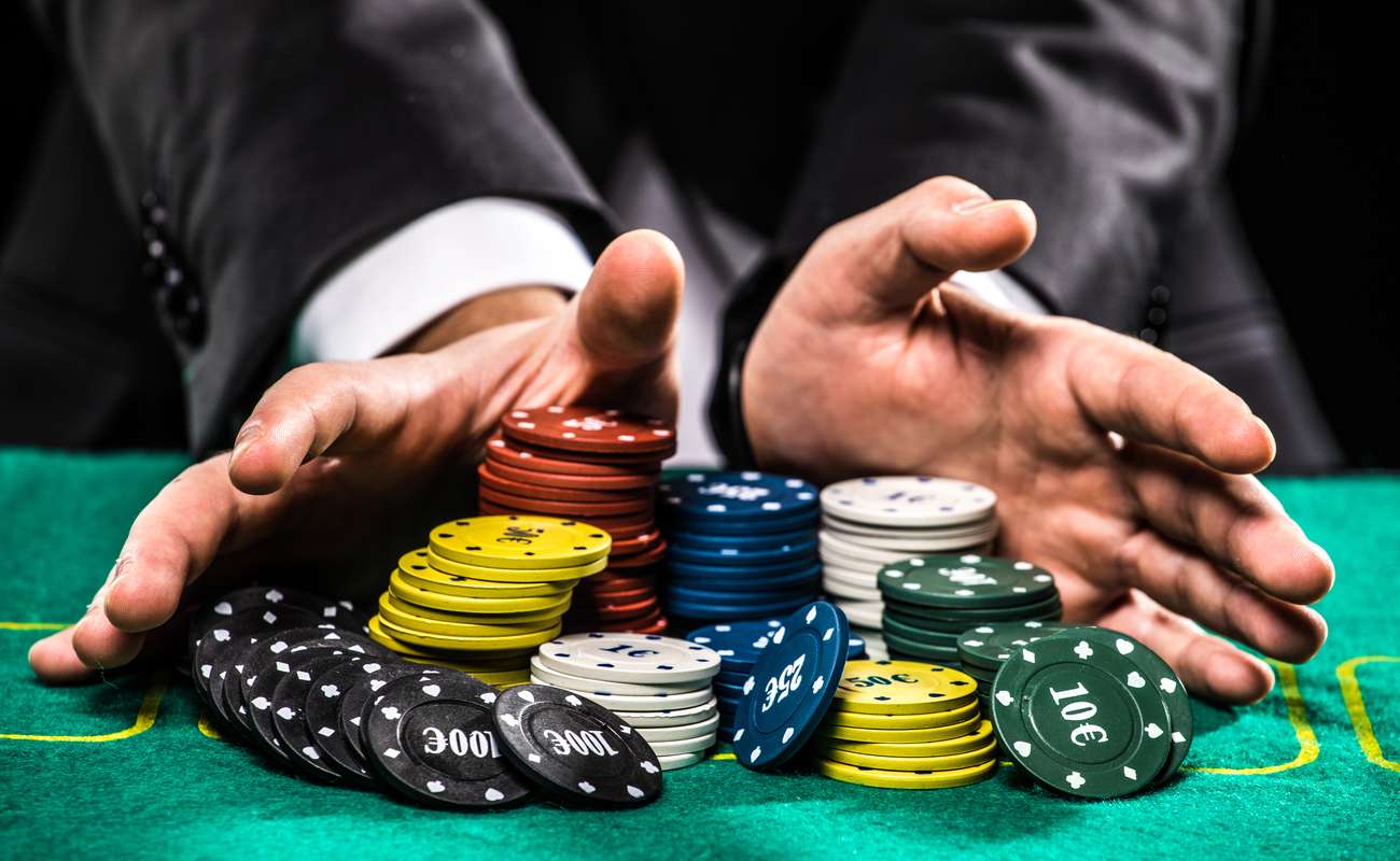 close up of poker player with chips at a green casino table