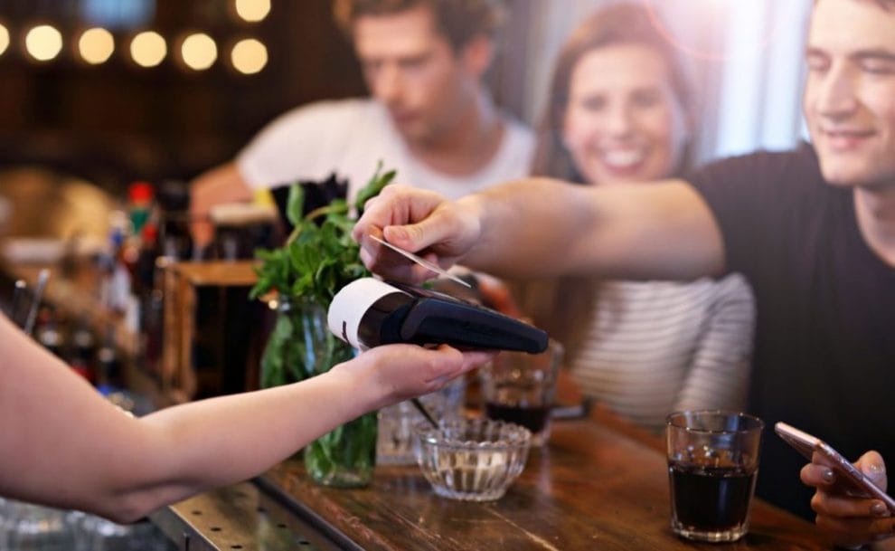 Group of friends paying for meal in restaurant using a bank card