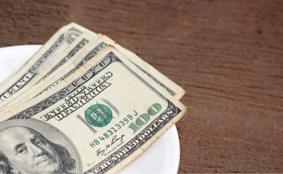 Dollar bills spread on plate as tip