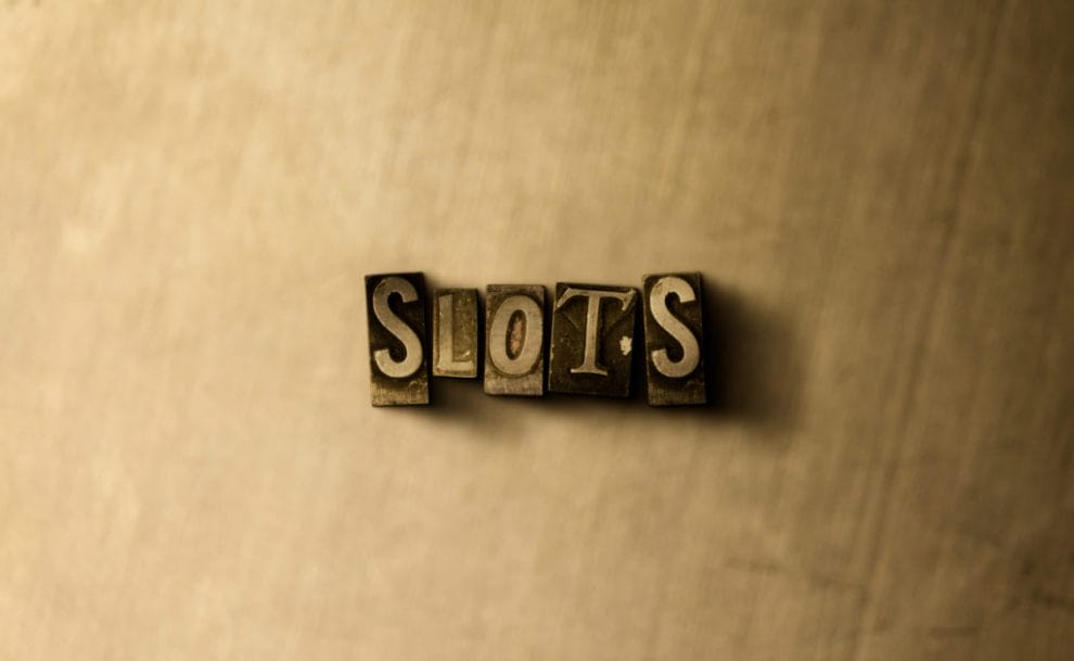close-up of grungy vintage typeset word saying "slot" on metal backdrop