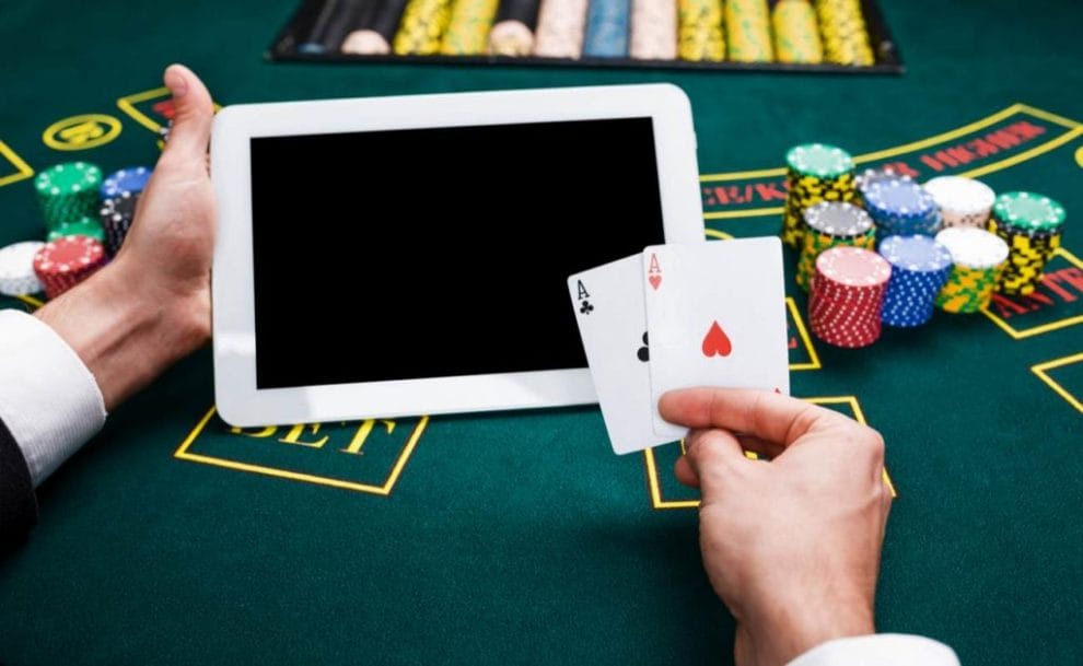 Hand holding cards and tablet device on blackjack table