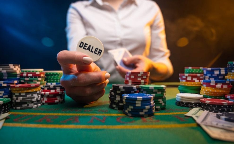 Casino dealer lifting dealer button surrounded by chips.