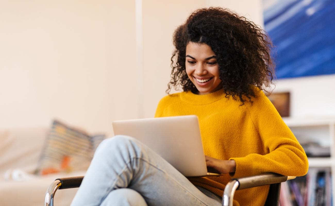  Young woman sitting in a chair with a laptop playing casino games