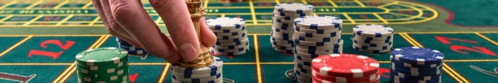 Close-up of a green roulette casino table with the hands of croupier and multicolored chips