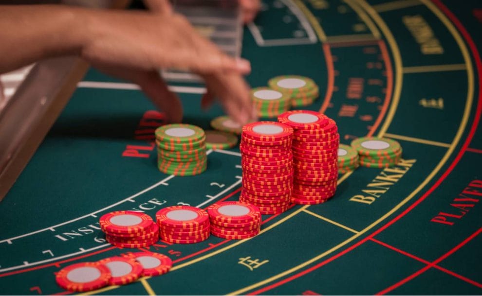 Hand of dealer organizing the red and green baccarat chips on gaming table