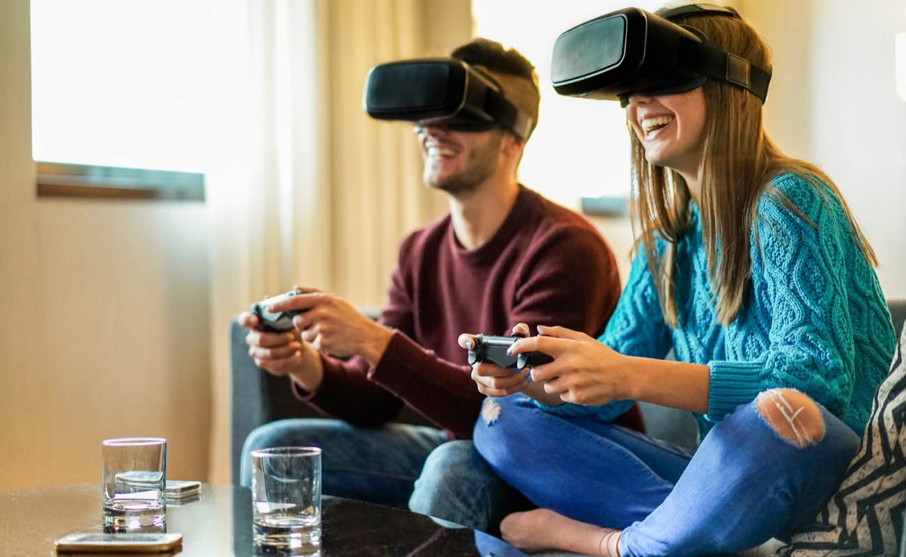 Couple playing video games wearing virtual reality glasses on the couch