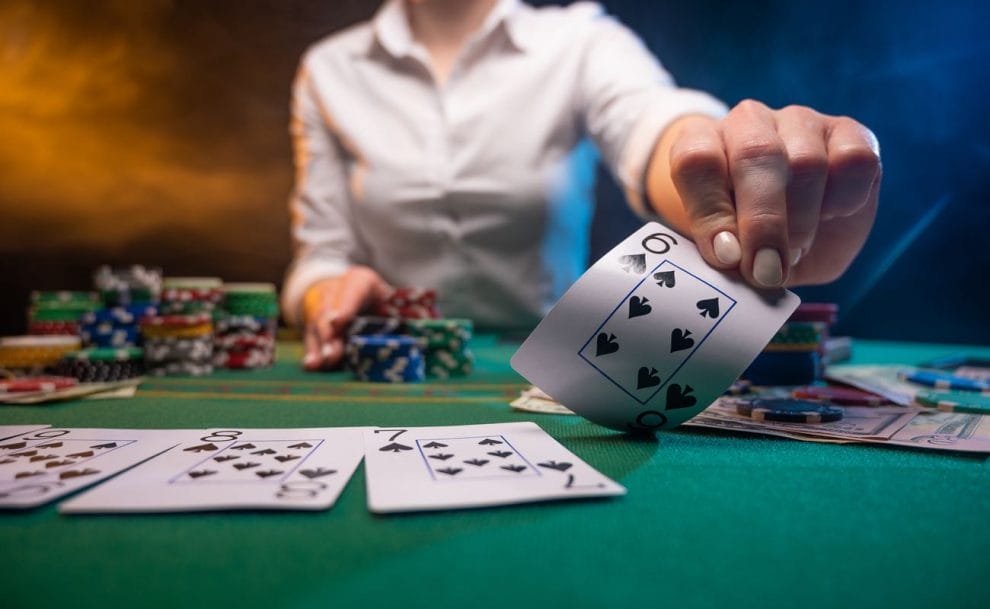 A croupier on a poker table holds up a six of spades