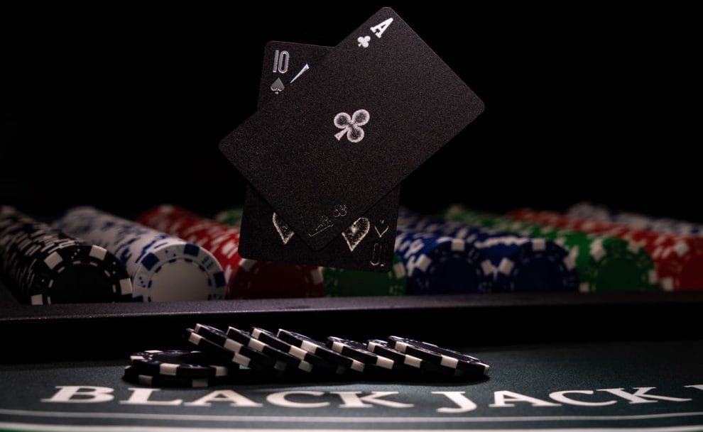 An ace of clubs and ten of spades float above a blackjack table.