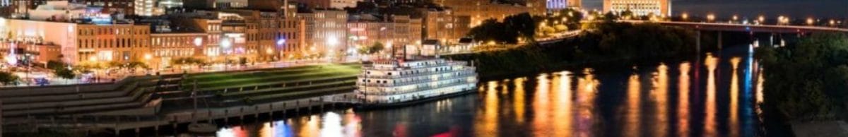 A riverboat alongside cityscape at night