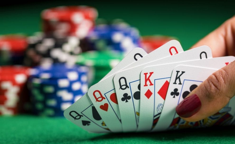 Poker hand showing three queens and two kings with casino chips in the background