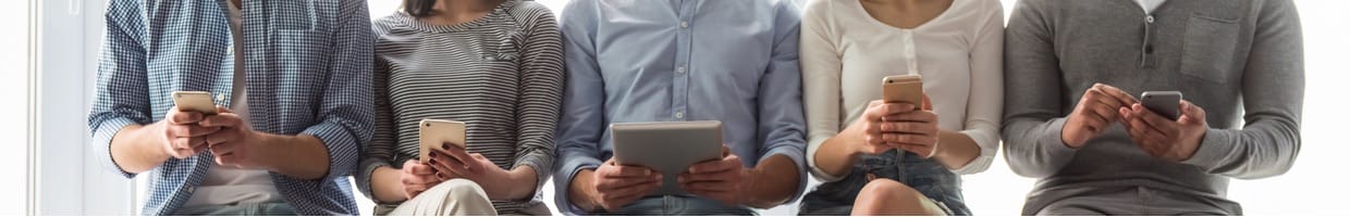 People in casual clothes using smart devices while sitting in a row.