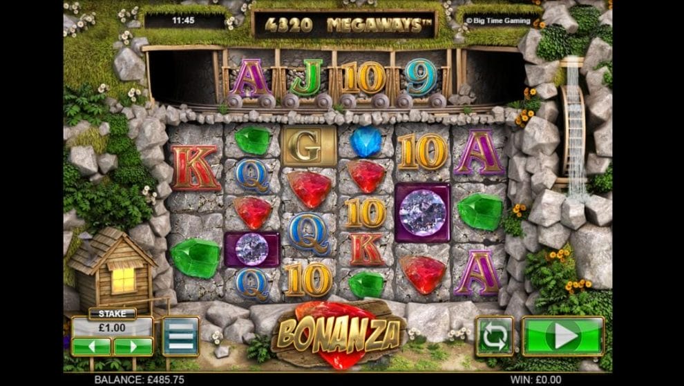 A screenshot of the game reels. The game reels are set in a mining quarry wall and are filled with various themed symbols, including green gems, red gems, blue gems, and diamonds, as well as A, K, Q, and other regular slot symbols. On the left of the reels is a mining shack, on the right is a water wheel, and above the reels is an extra row of symbols in four mining carts. Below the game reels are the game interface and the game logo.