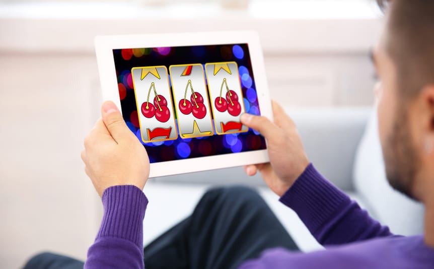 Man using a tablet to play online slot games.