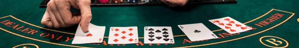 A dealer places cards face up on a green felt casino table.