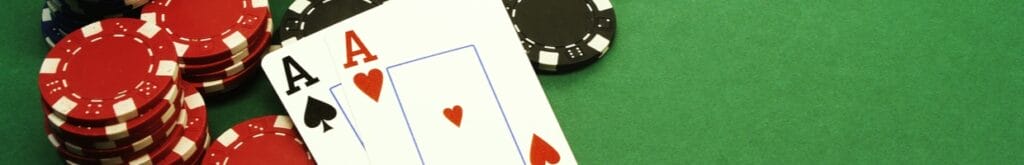 Пара тузов лежит против стопки фишек казино на зеленом войлочном столе казино.