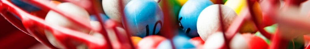 A red bingo cage filled with multicolored bingo balls.