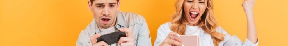 A young man and woman cheering and celebrating while playing mobile games.