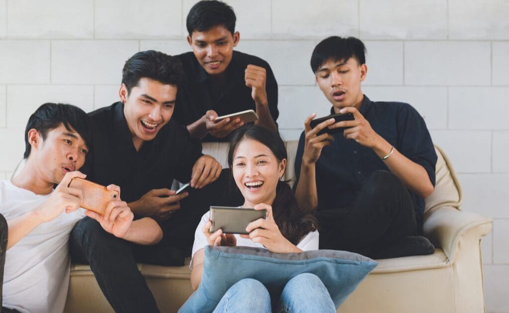  A group of friends enjoying themselves playing mobile games together.