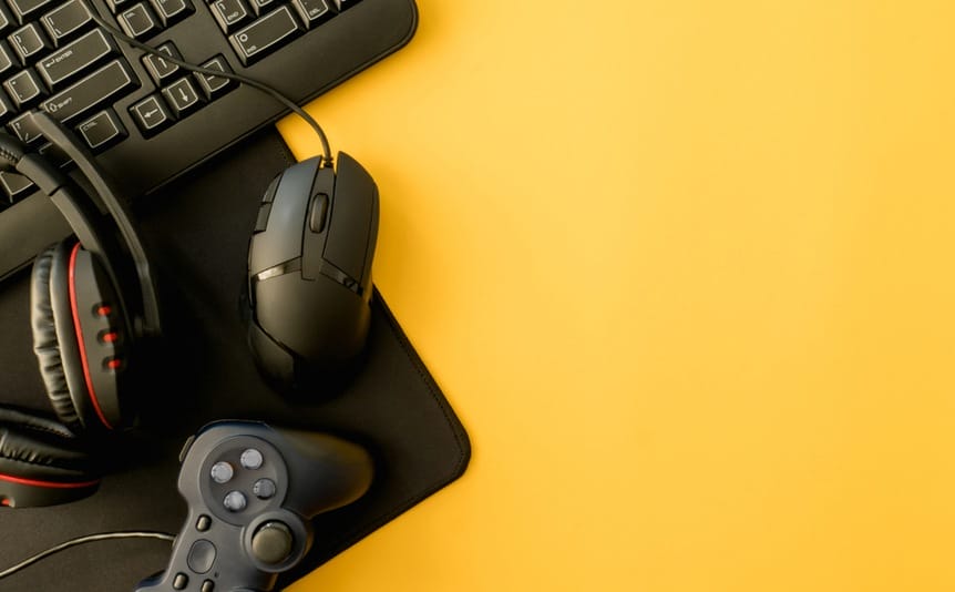 Gaming accessories, including a keyboard, mouse, headset, and controller on a yellow background.
