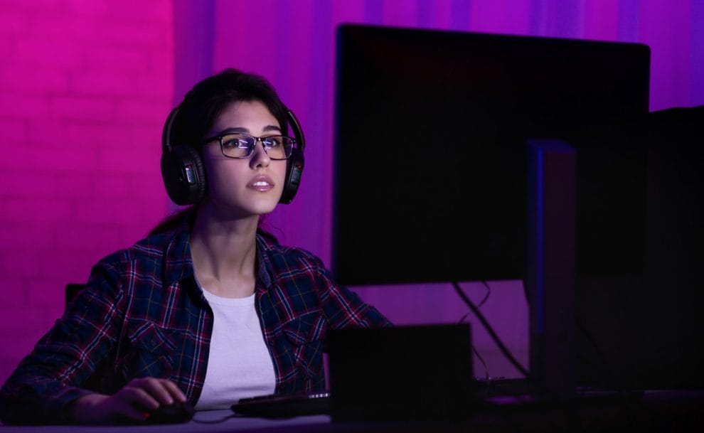 A young woman plays video games at her computer.
