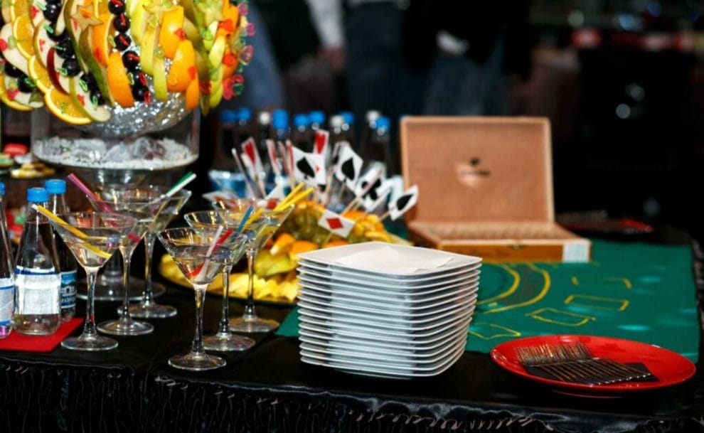 Platter of food with fruits and olives, with martini cocktails and plates on a casino table.

