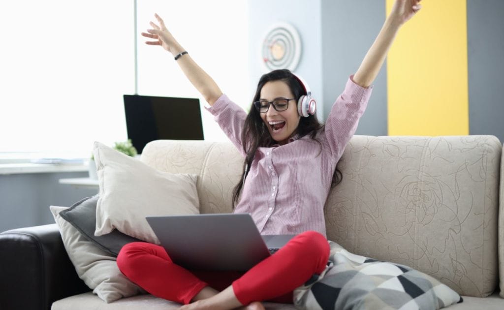 A young woman wearing headphones celebrates her bingo win.