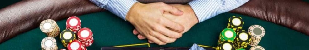 Closeup of poker player with playing cards, laptop, and chips