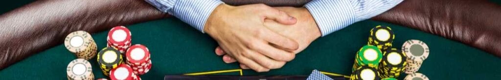 Closeup of poker player with playing cards, laptop, and chips