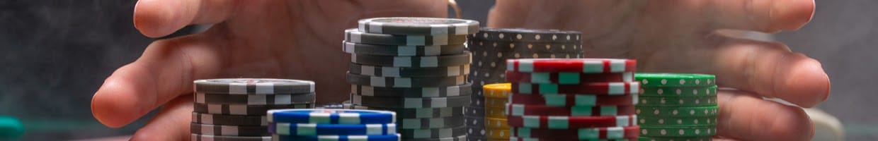Hands moving casino chips towards a winner.