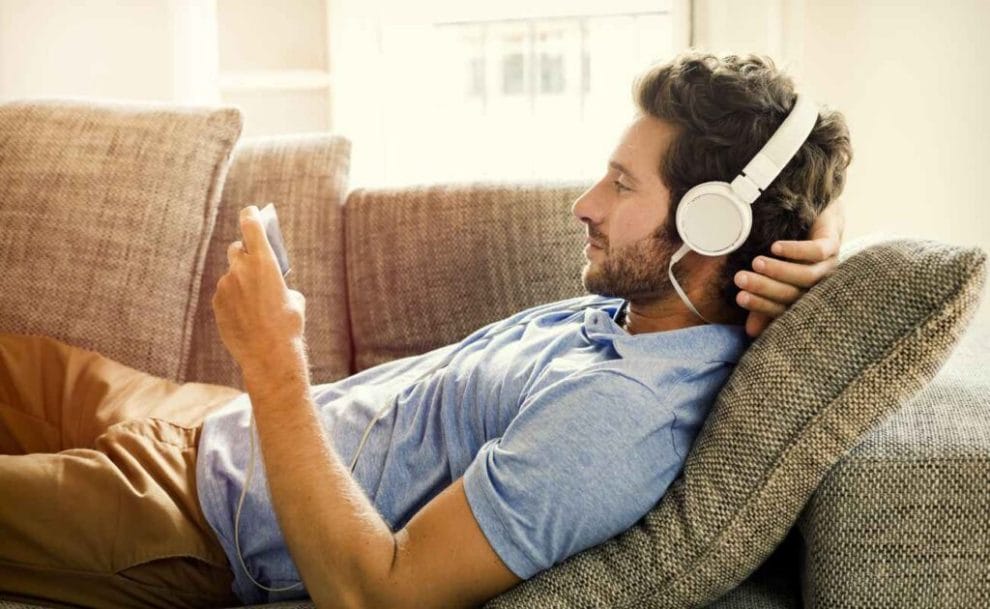 A man listening to music on a couch with headphones.
